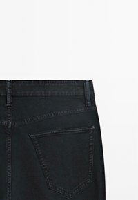 Jeans in denim nero con taglio dritto, dettagli di cucitura discreti e una singola tasca posteriore con forma classica.