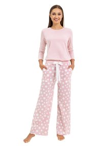Jasnoróżowa bluzka z długim rękawem w połączeniu z różowymi piżamowymi spodniami w kropki, które mają elastyczny pas i boczne kieszenie. Miękka tekstura materiału.