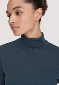 Dunkelblaues, geripptes Turtleneck-Oberteil mit taillierter Passform und hohem Kragen. Glatte Textur ohne sichtbare Muster oder Akzente.