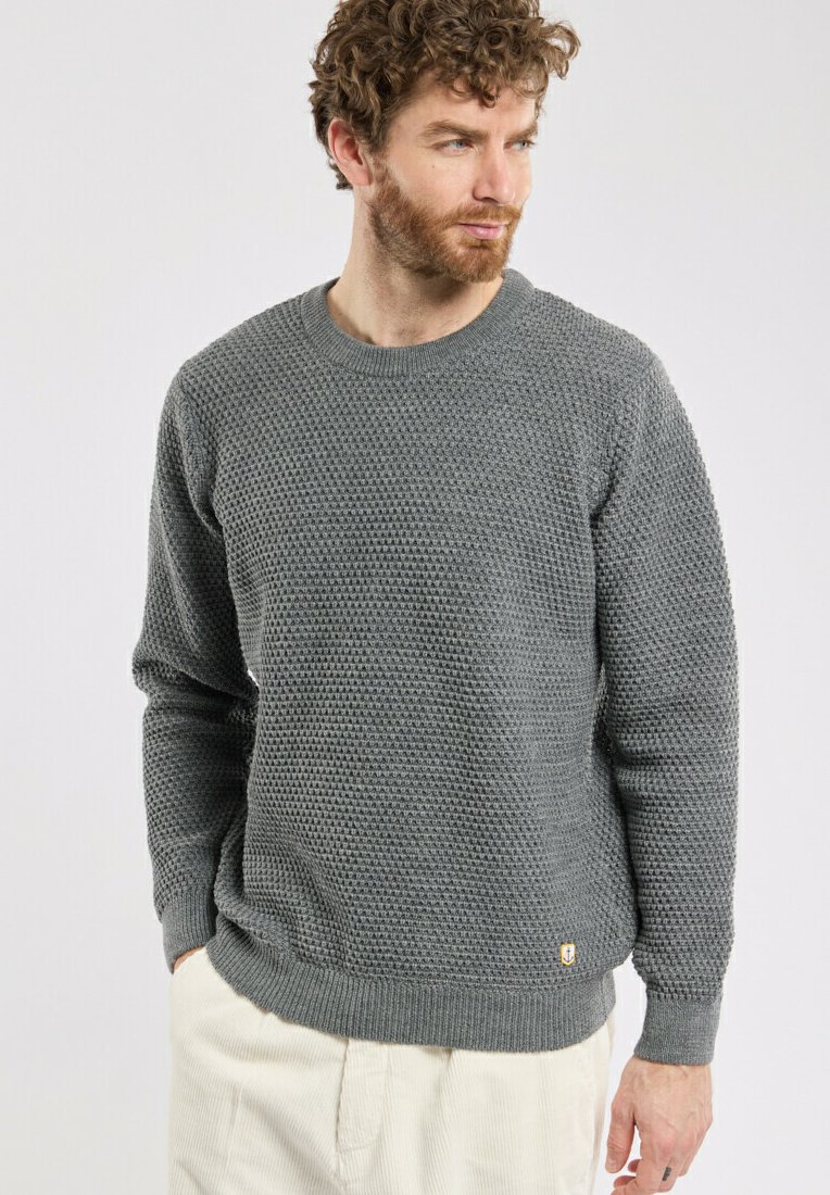 Pull en tricot gris avec un motif texturé, col rond, et bords côtelés aux poignets et à l'ourlet. Petite logo sur le bas à gauche.