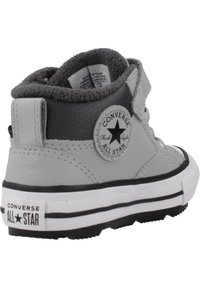 Baskets montantes en cuir gris avec des accents noirs, semelle en caoutchouc blanc, et un patch logo circulaire avec une étoile. Doublure intérieure en peluche visible.