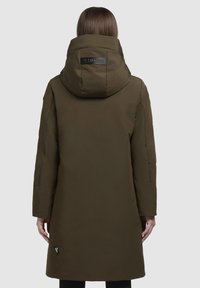Olivengrøn parka-jakke med hætte, der har et sort logo-patch, lange ærmer og en lige kant, designet til varme og dækning.