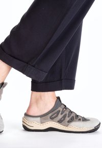 Gray and beige slip-on shoes with cut-out design and rubber soles, paired with rolled navy pants, showcasing a casual, breathable style.