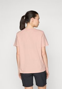 Lys rosa bomull t-skjorte med korte ermer og rund hals, kombinert med mørke shorts; glatt tekstur, avslappet passform.