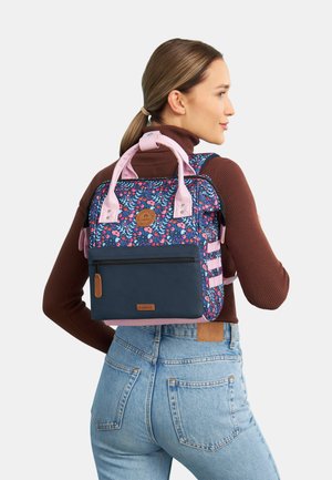 Sac à dos à motif floral en bleu et rose, avec une poche zippée à l'avant, des poignées supérieures doubles et des bretelles réglables. Fini en tissu texturé.