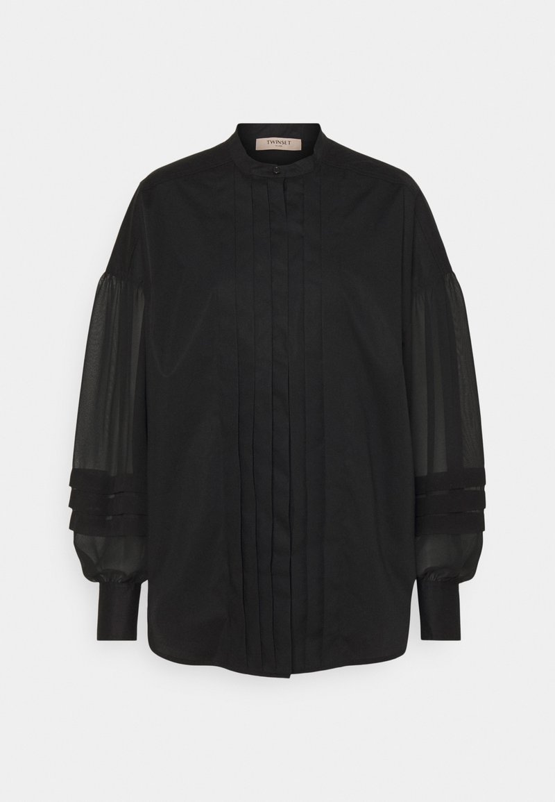 Chemise noire avec col montant, devant plissé et manches bouffantes transparentes avec accents de tissu superposés. Texture lisse et design classique.