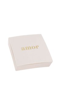 Kvadratisk, krämfärgad låda med en slät yta, med ordet "amor" i guldtext på toppen. Framhävda kanter.