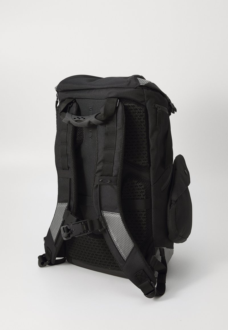 Sac à dos noir avec des bretelles rembourrées, un panneau arrière en mesh, une sangle de poitrine réglable, une poche latérale et des accents réfléchissants. Matériau durable.