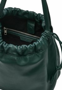 Zielona skórzana torba w kształcie wiadra z marszczonym otwarciem, wewnętrzną kieszenią na zamek i gładką teksturą. Posiada czarne wykończenie i zapięcie na sznurki.
