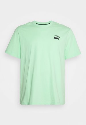 T-shirt en coton vert menthe avec des manches courtes, col rond et un petit logo Lacoste noir brodé sur la poitrine gauche.