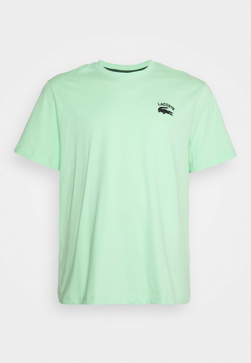 T-shirt en coton vert menthe avec des manches courtes, col rond et un petit logo Lacoste noir brodé sur la poitrine gauche.