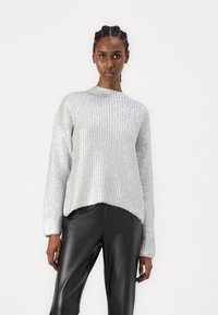 Söljig, texturerad tröja med ribbat mönster och hög krage, kombinerad med eleganta svarta läderbyxor; avslappnad passform med rundad nederkant.