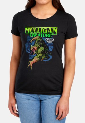 Woman wearing black t-shirt with green "Mulligan Creature" text and graphic of a green monster from Stranger Things TV show.