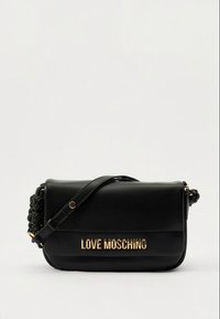 Černá crossbody taška Moschino s nápisem ve zlatých písmech, nastavitelným popruhem a pletenými detaily na bocích na jednobarevném pozadí.