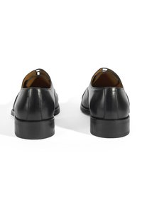 Chaussures en cuir noir avec une finition lisse, forme arrondie et un petit talon carré. Présentent une petite découpe à l'arrière pour un enfilage facile.