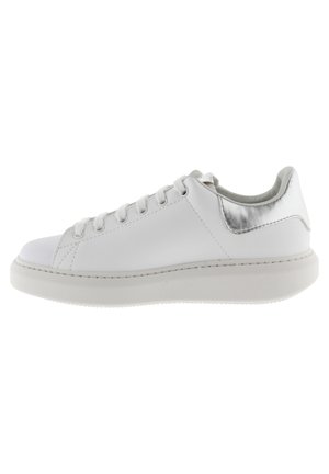 Zapatilla de cuero blanca con un acabado suave, punta redonda, acento plateado en el talón y suela de goma plana. Presenta seis ojales para los cordones.