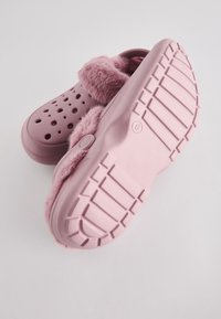 Pair of pink clogs with ventilation holes, soft faux fur lining, and thick textured soles on a plain light background.