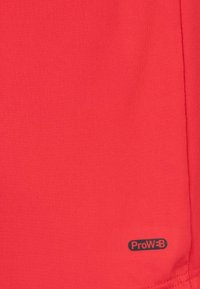 Tejido de poliéster rojo con textura suave, que presenta un pequeño logotipo negro etiquetado como "ProW÷B" cerca de la esquina inferior derecha.