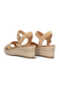 Beige suede wedge sandals with multiple cross straps and adjustable buckle. Jute-wrapped sole with textured detailing. Soft inner lining.