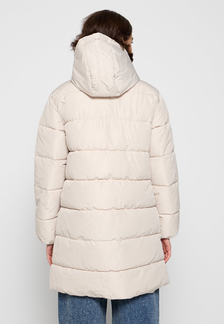 Abrigo acolchado de color beige claro con capucha, textura acolchada, mangas largas y una silueta ligeramente acampanada, que se extiende por debajo de las caderas.