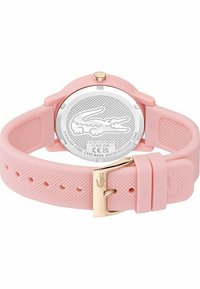 Montre en silicone rose, ronde, avec un bracelet texturé, une boucle en or et un dos en acier inoxydable arborant un design de logo. Résistante à l'eau jusqu'à 5 bars.