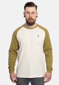 Langekortoef T-shirt met crème lichaam en olijfgroene mouwen. Heeft een klein zwart berenlogo op de borst. Gemaakt van katoen.