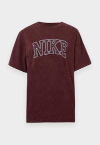 Burgundijas kokvilnas T-krekls ar īsām piedurknēm, ar baltu kontūru "NIKE" logo uz krūtīm. Mīksta, teksturēta apdare.