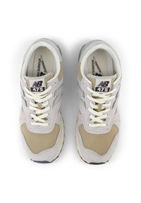 Sneakers New Balance 475 in rosa chiaro e beige, con una combinazione di materiali in suede e tessuto, lacci rotondi e suola in gomma.