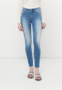 Hubené modré džíny z denimu s vybledlým povrchem, vysokým pasem, standardním pětipocket designem a jemnými detaily šití.
