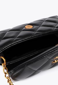 Borsa a tracolla nera trapuntata con una chiusura dorata, parzialmente aperta per rivelare un interno vuoto e una tracolla a catena sul lato.