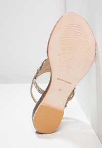 Lædersandal med en struktureret, metallisk finish; et åbent bagside-design; glat, lysfarvet sål med præget mønster og størrelse 37.
