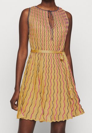 Złota sukienka bez rękawów z pionowymi, różowymi i czarnymi falistymi paskami, dekoltem z wycięciem na sznurki i dopasowanym paskiem w talii.