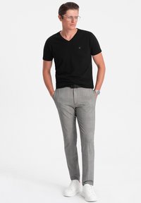 Sort kortærmet V-hals t-shirt kombineret med gråternet skræddersyede bukser, fuldendt med hvide sneakers og et sølvur.