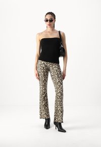 Melna adīta bezplecu blūze, leopardu raksta platu džinsu bikses un melni augstpapēžu potīšu zābaki. Aksesuāri: melnas saulesbrilles un rokassoma.