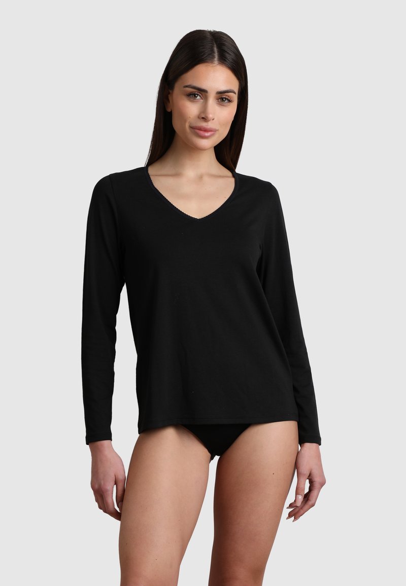 Maglietta nera a maniche lunghe in una vestibilità rilassata con scollatura a V, realizzata in tessuto morbido e con dettagli di cucitura minimi. Abbinata a un paio di pantaloni intimi neri.