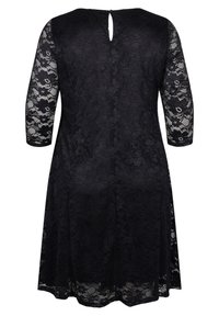 Robe noire longueur genou avec motif en dentelle florale, manches trois-quarts en dentelle, et petite ouverture en forme de goutte dans le dos au niveau du col.