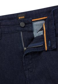Tmavomodré džínsy so zipsom, zapínaním na gombík a oranžovým akcentom na vnútornom páse, s nášivkou BOSS.