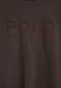 Brun bomulls t-shirt med en stor mörkbrun "POLO CLUB" tryck. Rund halsringning och mjukt, strukturerat tyg.