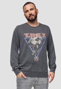 Grijze sweatshirt met lange mouwen, voorzien van een T. Rex-graphic, een blauw driehoekontwerp en de tekst "1993 Tour" onderaan. Zachte textuur, casual pasvorm.