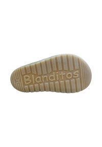 Suela de un zapato, con un material de goma texturizado en beige claro, con estrías horizontales y verticales, y el texto "Blanditos".