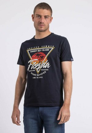 T-shirt en coton bleu marine avec impression graphique représentant des palmiers et du texte. Manches courtes, col rond et coupe décontractée. Design décontracté.