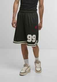 Black basketball shorts with white stripes, featuring a large white "99" on one side and a small red logo. Worn with light-colored sneakers.