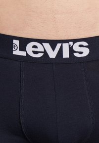Marineblaue Baumwoll-Boxershorts mit einem weißen Levi's-Logo am Taillenbund und sichtbaren Nahtdetails.