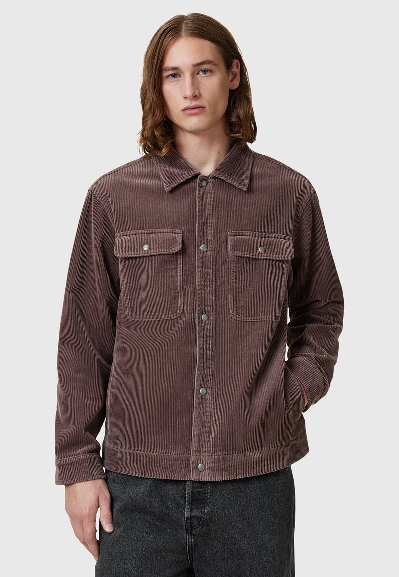 Brun kordflor skjortjacka med två bröstfickor, framknäppning med tryckknappar och klassisk krage; textil med struktur och avslappnad passform.