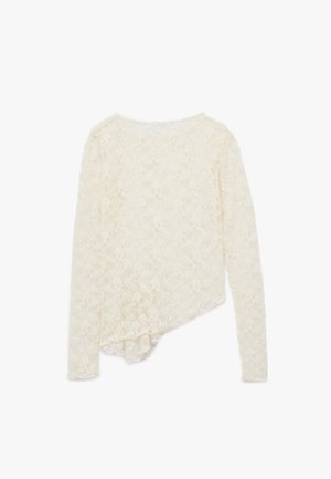 Top de encaje de manga larga en color blanco roto; presenta un dobladillo asimétrico y un intrincado patrón floral. Tela suave y texturizada con cuello redondo.