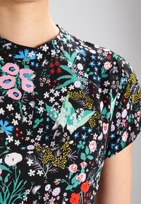Svart tyg med blommönster som har rosa, blå, gröna och vita inslag. Korta ärmar och rund halsringning.