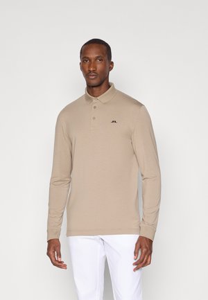 Ilga rankovė polo marškinėliai iš smėlio spalvos medžiagos. Savybės: apykaklė, trys mygtukai ir mažas juodas logotipas ant krūtinės. Paprastas dizainas, glotni tekstūra.
