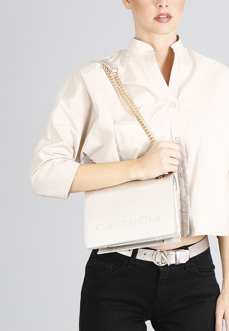Borsa a tracolla beige con tracolla a catena, texture liscia, logo impresso "CAFÉ NOIR" e forma rettangolare elegante.