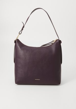 Purple leather handbag with a textured finish, a single adjustable strap, a gold zipper, and a logo embossed on the front.