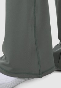 Pantaloni attivi verdi con una texture liscia, caratterizzati da una cucitura lungo i lati, progettati per comfort e movimento.